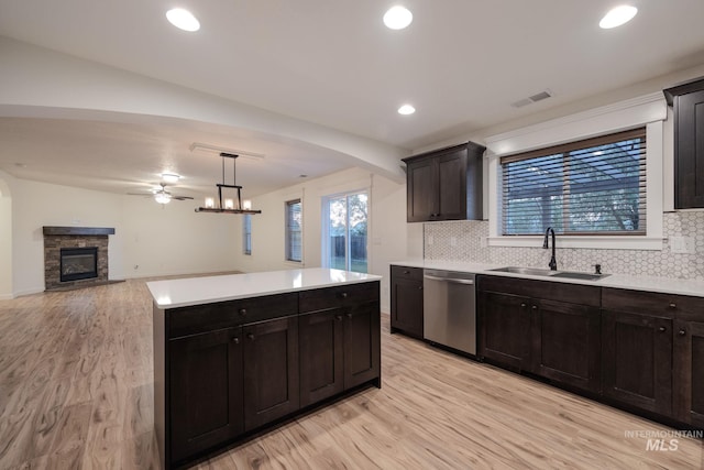 12476 W Kempshire Ct, Star, ID 83669 - kitchen with dishwasher, light wood-style floors, a fireplace, backsplash, and recessed lighting