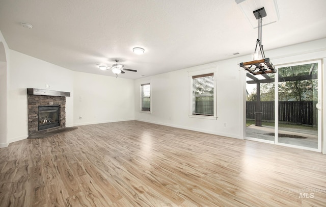 12476 W Kempshire Ct, Star, ID 83669 - unfurnished living room with a ceiling fan, light wood-type flooring, and a stone fireplace