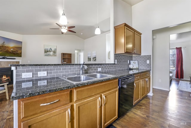 kitchen featuring dishwasher, vaulted ceiling, a tile fireplace, dark wood-style floors, and a sink