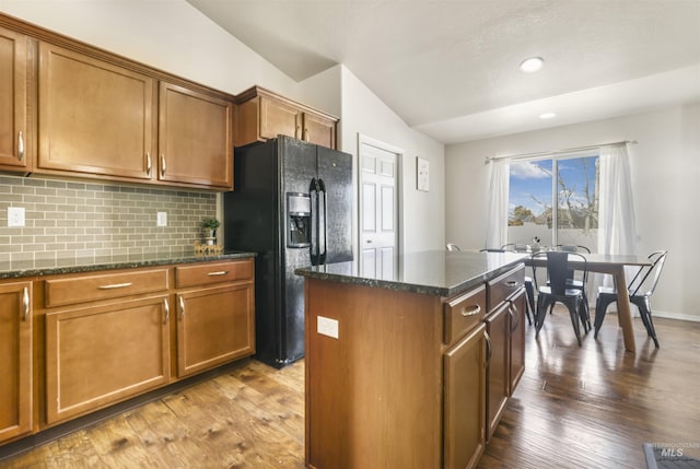 kitchen featuring tasteful backsplash, a kitchen island, wood finished floors, and black refrigerator with ice dispenser