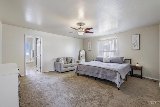 carpeted bedroom with ensuite bath, baseboards, and a ceiling fan