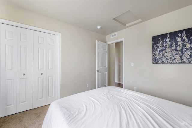 carpeted bedroom with attic access, visible vents, and a closet