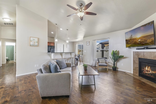 living room with visible vents, dark wood-style floors, a fireplace, and vaulted ceiling