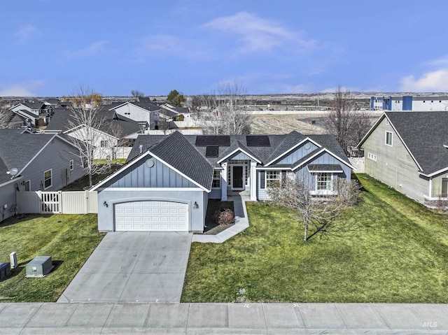 view of front of property with a front lawn, concrete driveway, fence, and board and batten siding