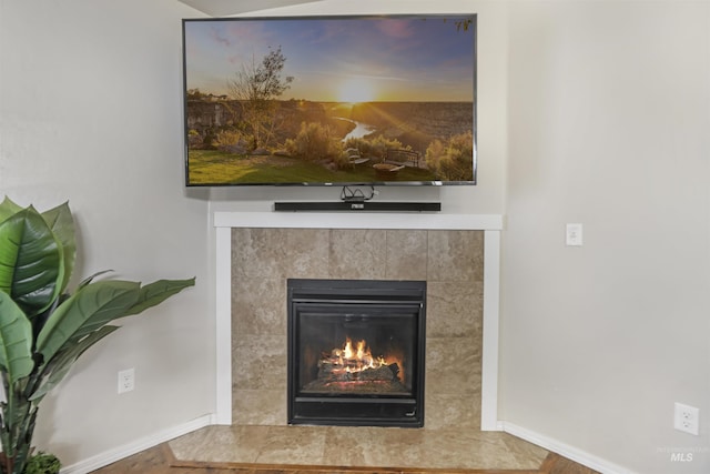 interior details with baseboards and a tile fireplace