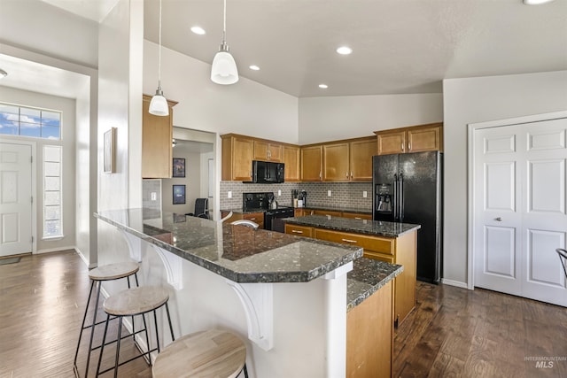 kitchen featuring backsplash, a center island, dark wood-type flooring, brown cabinets, and black appliances