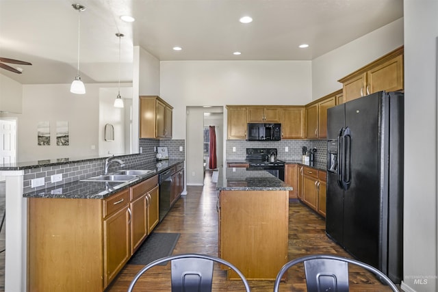 kitchen with a kitchen island, dark stone countertops, brown cabinets, dark wood-style floors, and black appliances