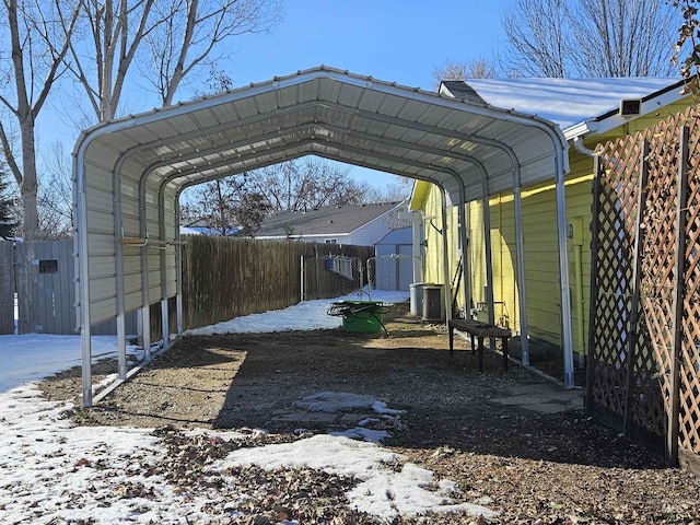 snow covered parking area with a carport