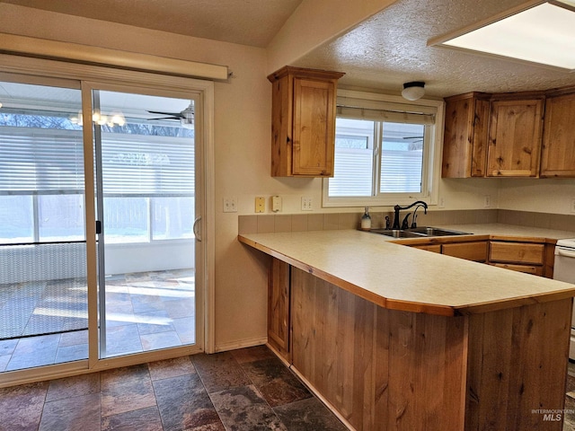 kitchen featuring kitchen peninsula, sink, a textured ceiling, and stove