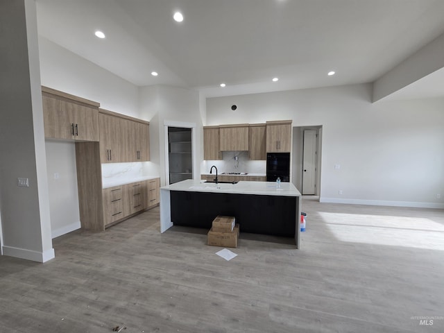 kitchen with modern cabinets, a center island with sink, light countertops, baseboards, and recessed lighting
