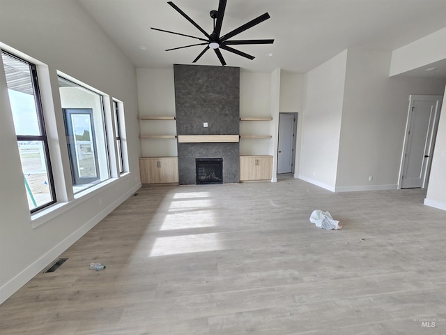 unfurnished living room with baseboards, a tile fireplace, ceiling fan, and light wood finished floors
