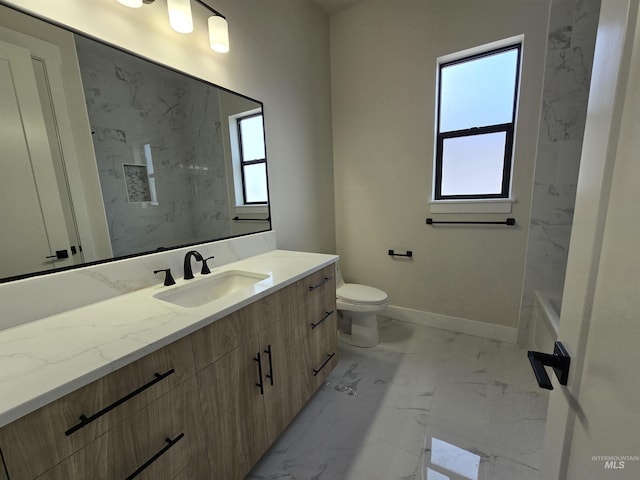 bathroom with marble look tile flooring, baseboards, vanity, toilet, and a tub