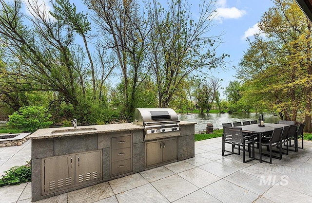 1040 W Bogus Vw, Eagle, ID 83616 - view of patio / terrace featuring a water view, a grill, a sink, outdoor dining area, and an outdoor kitchen