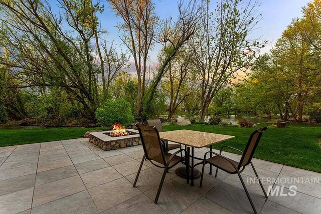 1040 W Bogus Vw, Eagle, ID 83616 - patio terrace at dusk with an outdoor fire pit and a lawn