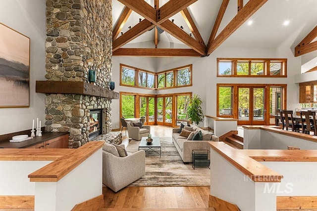 1040 W Bogus Vw, Eagle, ID 83616 - living area featuring hardwood / wood-style flooring, beam ceiling, high vaulted ceiling, a wealth of natural light, and a stone fireplace