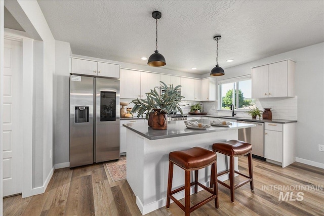 4849 N Willowside Ave, Meridian, ID 83646 - kitchen featuring appliances with stainless steel finishes, dark countertops, tasteful backsplash, light wood-style flooring, and recessed lighting