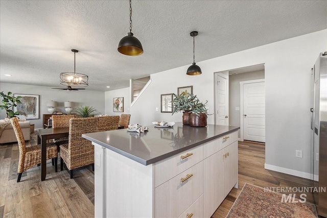 4849 N Willowside Ave, Meridian, ID 83646 - kitchen with wood finished floors, decorative light fixtures, a textured ceiling, dark countertops, and a kitchen island
