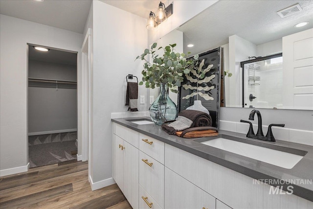 4849 N Willowside Ave, Meridian, ID 83646 - full bathroom with double vanity, tiled shower, a spacious closet, wood finished floors, and baseboards