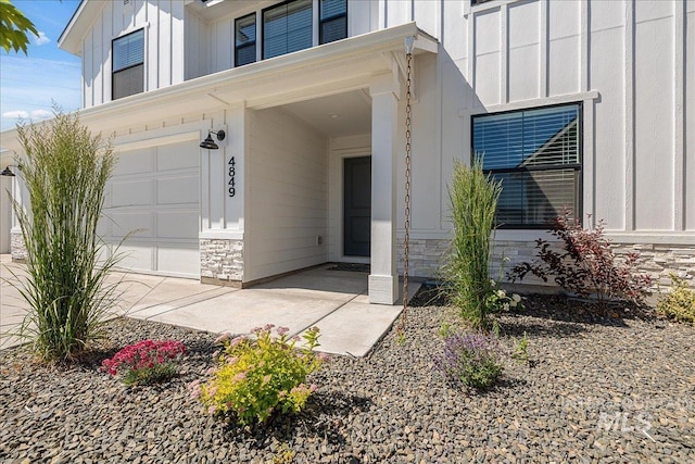 4849 N Willowside Ave, Meridian, ID 83646 - view of exterior entry with board and batten siding, stone siding, and an attached garage