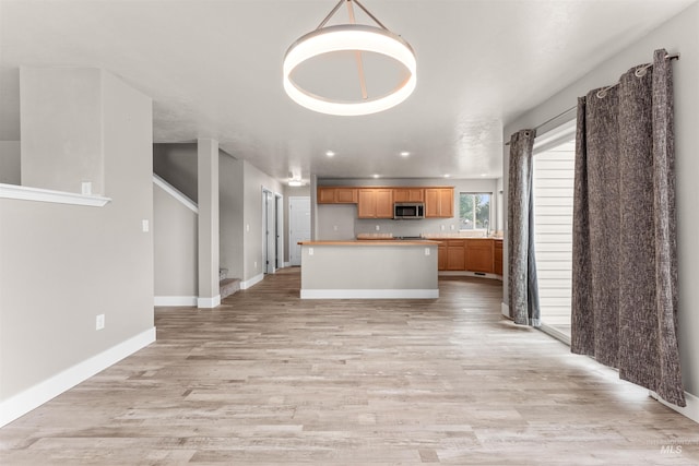 5291 N Midnight Haze Way, Meridian, ID 83646 - kitchen with stainless steel microwave, light countertops, light wood-type flooring, a kitchen island, and open floor plan