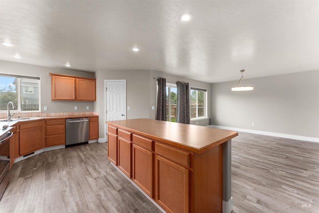 5291 N Midnight Haze Way, Meridian, ID 83646 - kitchen featuring stainless steel dishwasher, light wood finished floors, a kitchen island, recessed lighting, and light countertops