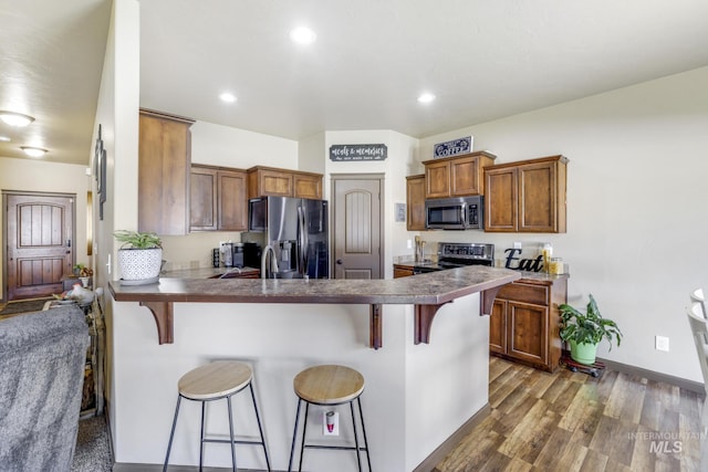812 Kelli Ln, Filer, ID 83328 - kitchen with dark wood-type flooring, a peninsula, a breakfast bar, and appliances with stainless steel finishes