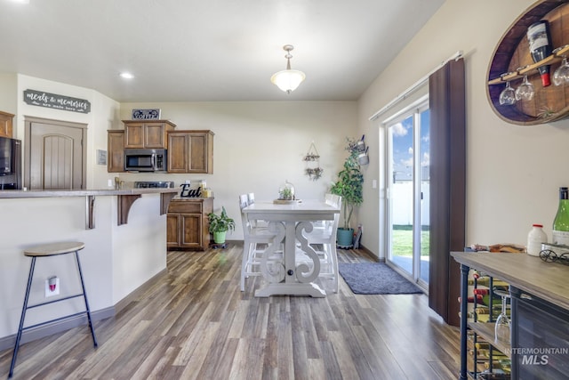 812 Kelli Ln, Filer, ID 83328 - kitchen with light countertops, a kitchen breakfast bar, brown cabinets, stainless steel microwave, and wood finished floors