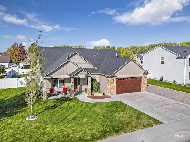 812 Kelli Ln, Filer, ID 83328 - view of front of home featuring a front yard, stone siding, fence, an attached garage, and concrete driveway
