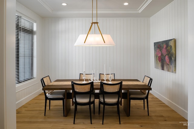 dining room with a tray ceiling, light wood-type flooring, and crown molding