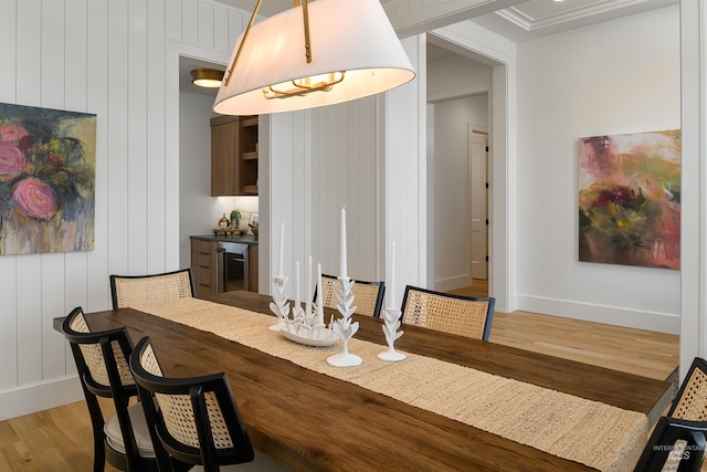 dining space featuring beverage cooler, crown molding, and hardwood / wood-style floors