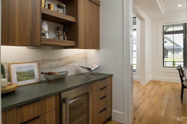 bar with wine cooler, ornamental molding, and light wood-type flooring