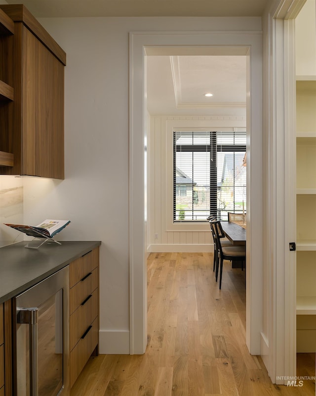 interior space featuring light hardwood / wood-style flooring, beverage cooler, and a tray ceiling