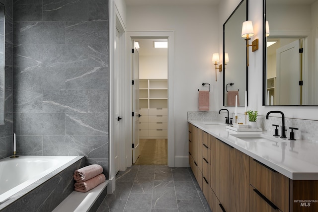 bathroom with tile walls, tile floors, large vanity, dual sinks, and a bathing tub