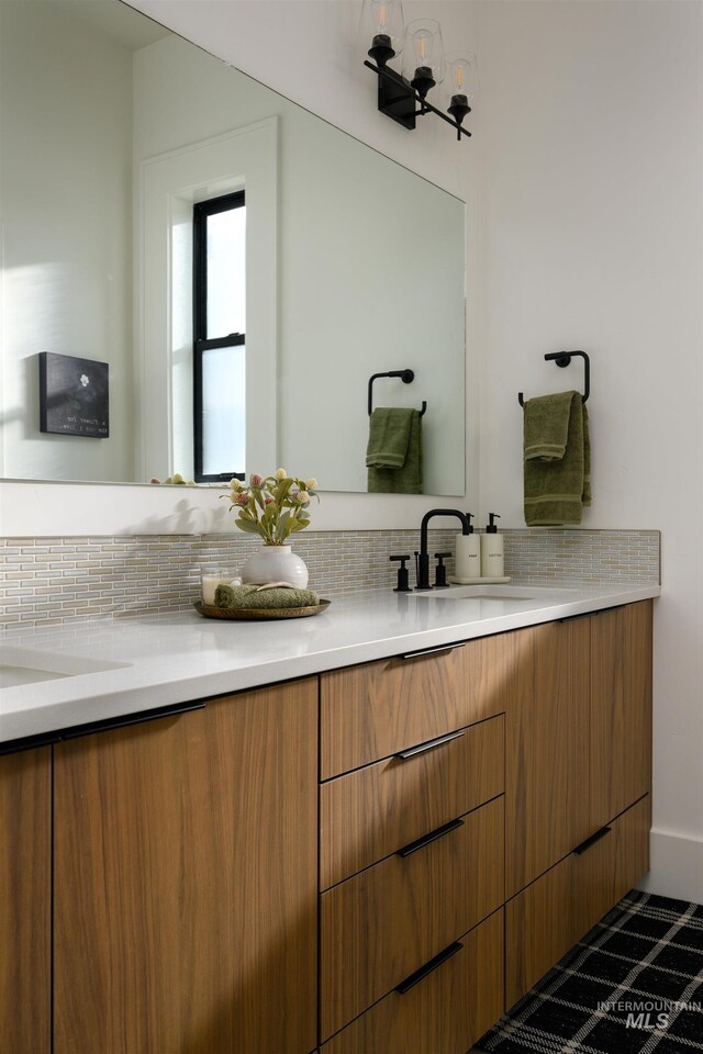 bathroom featuring tile flooring, dual vanity, and tasteful backsplash