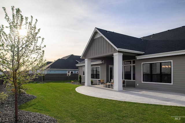 back house at dusk with a yard and a patio