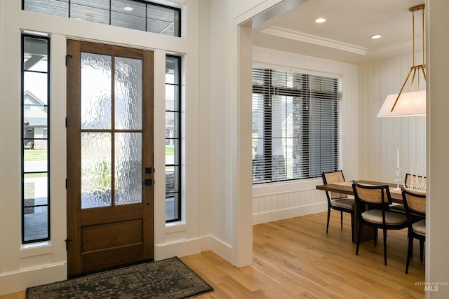 foyer with crown molding, a wealth of natural light, and light hardwood / wood-style floors