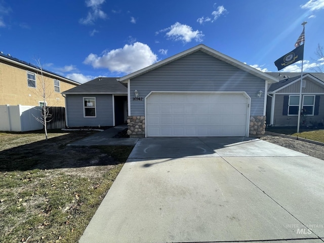 ranch-style home featuring an attached garage, stone siding, fence, and concrete driveway