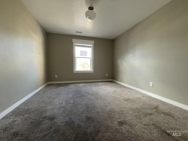 spare room with visible vents, a textured ceiling, baseboards, and carpet flooring