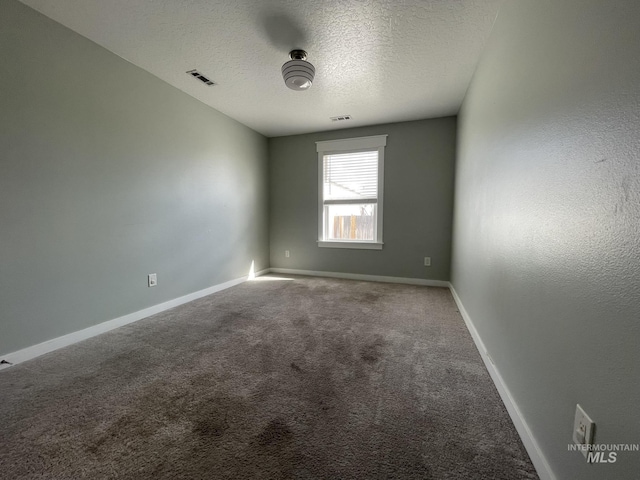 carpeted spare room featuring visible vents, a textured ceiling, and baseboards