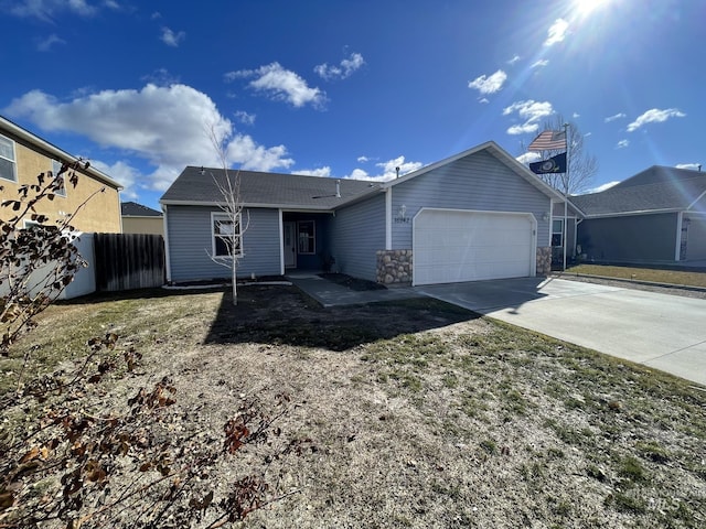 single story home featuring driveway, stone siding, an attached garage, and fence