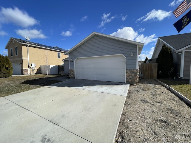 view of side of property featuring a garage, an outbuilding, stone siding, and fence