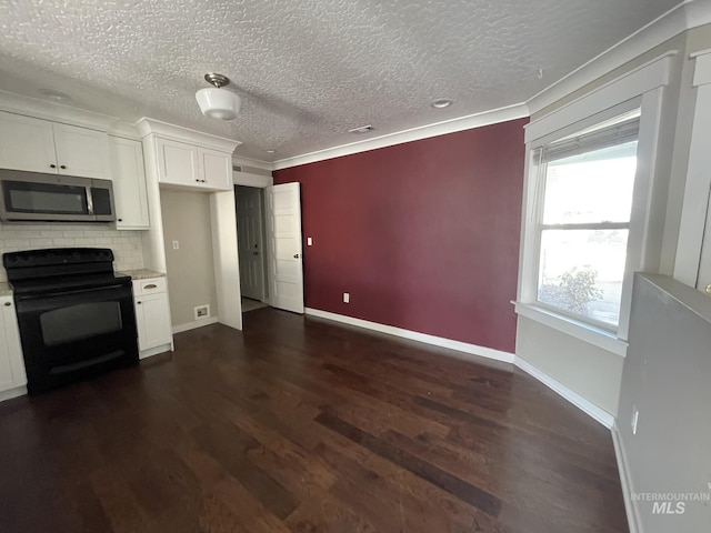 kitchen with dark wood finished floors, stainless steel microwave, black range with electric stovetop, white cabinetry, and baseboards