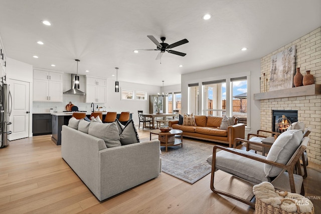 205 S Sunniva Ave, Kuna, ID 83634 - living room with a ceiling fan, recessed lighting, light wood-type flooring, a fireplace, and a chandelier