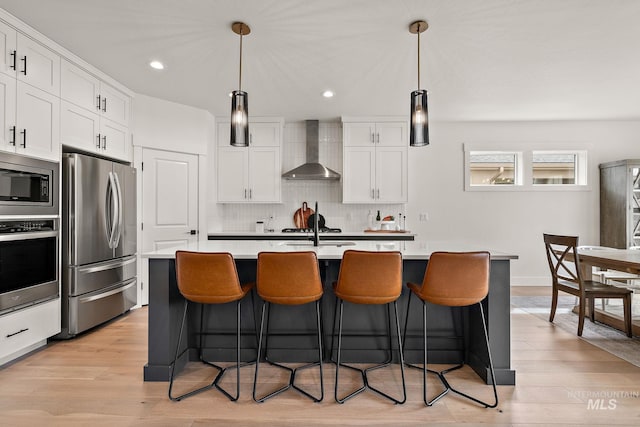 205 S Sunniva Ave, Kuna, ID 83634 - kitchen with wall chimney range hood, appliances with stainless steel finishes, light wood-type flooring, light countertops, and recessed lighting