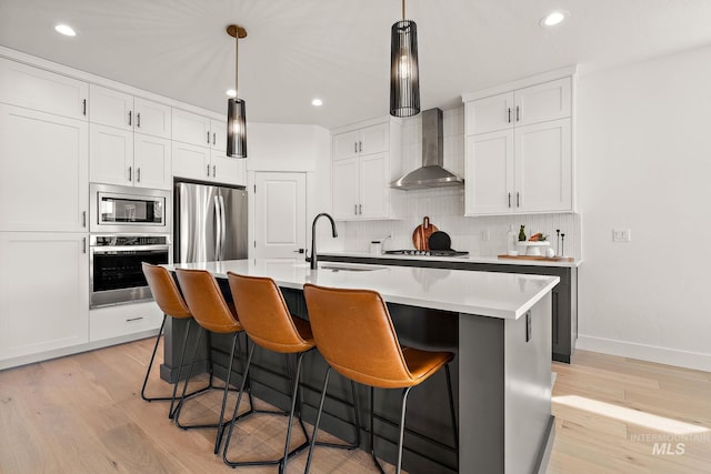 205 S Sunniva Ave, Kuna, ID 83634 - kitchen featuring stainless steel appliances, wall chimney range hood, tasteful backsplash, light wood-style floors, and recessed lighting