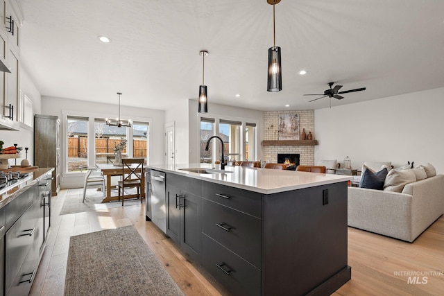 205 S Sunniva Ave, Kuna, ID 83634 - kitchen featuring a sink, stainless steel appliances, dark cabinets, a fireplace, and light countertops