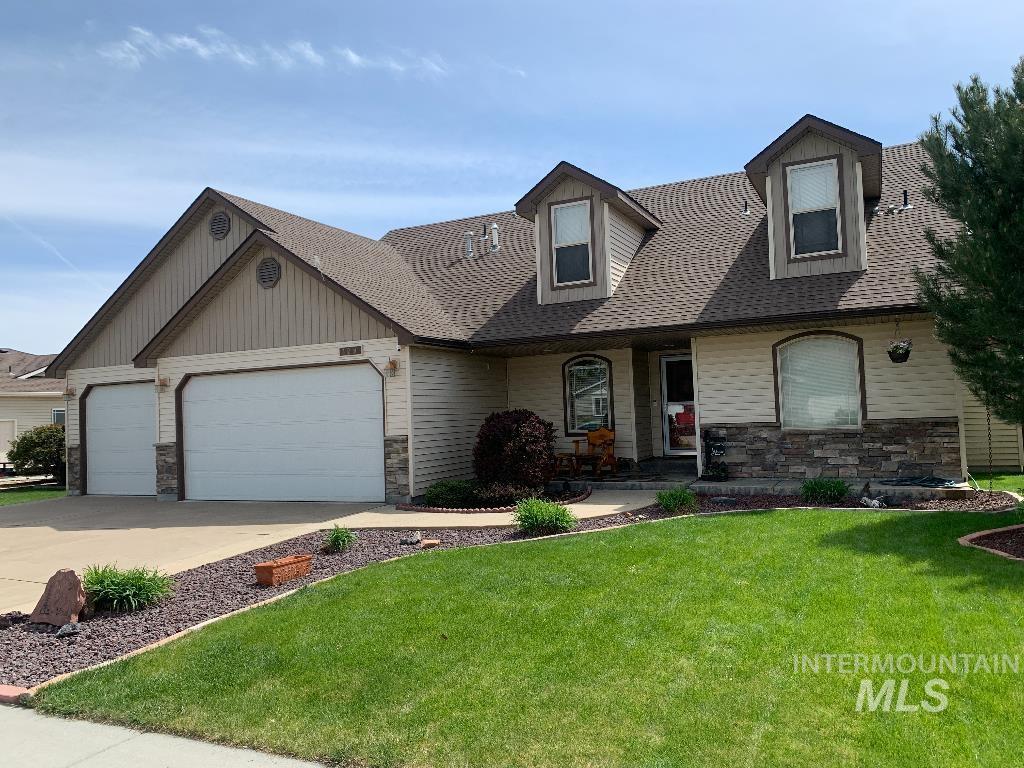 129 Lightning St, Mountain Home, ID 83647 - view of front facade with concrete driveway, stone siding, a shingled roof, a front yard, and an attached garage