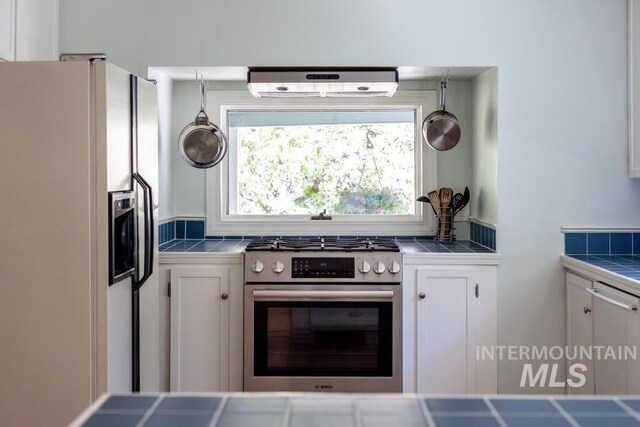 517 E C St, Moscow, ID 83843 - kitchen featuring tile countertops, white refrigerator with ice dispenser, and stainless steel gas range oven