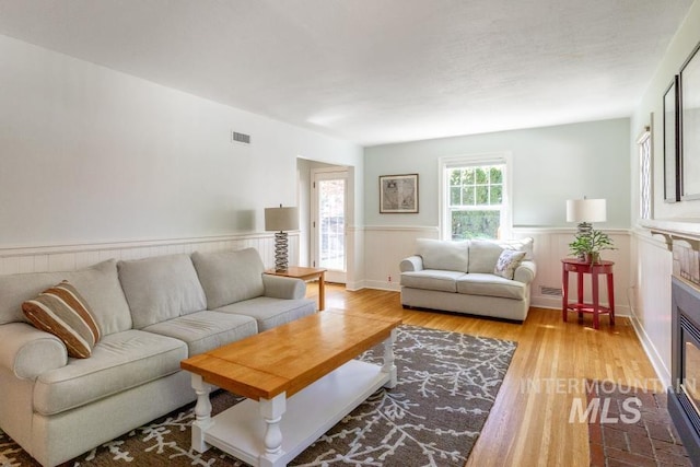 517 E C St, Moscow, ID 83843 - living room featuring wainscoting, a glass covered fireplace, and light wood-style flooring