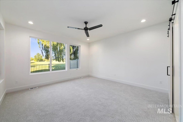 spare room with ceiling fan and light colored carpet